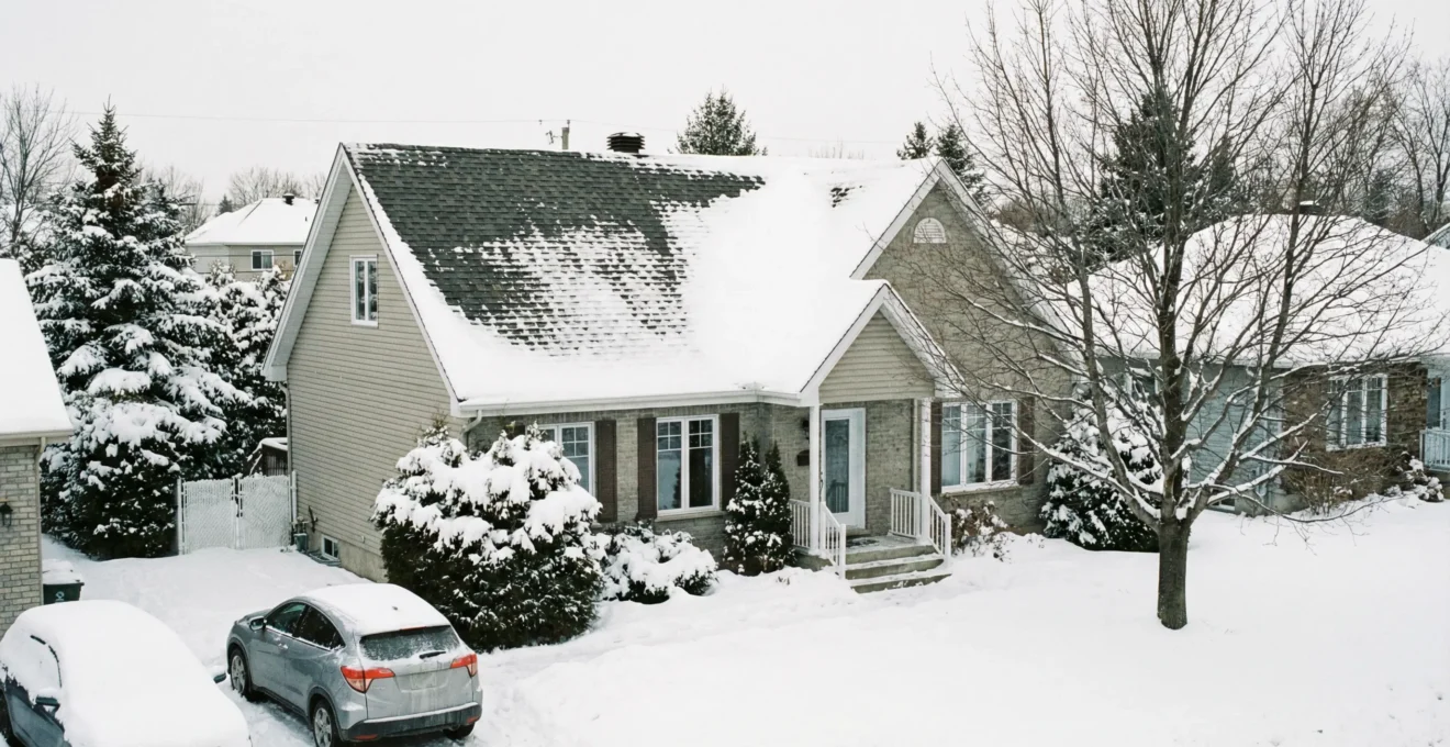 Toiture résidentielle québécoise avec bardeaux d'asphalte partiellement recouverts de neige en hiver