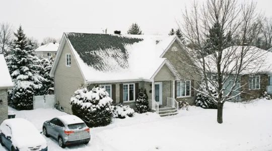 Toiture résidentielle québécoise avec bardeaux d'asphalte partiellement recouverts de neige en hiver